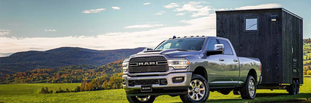 2023 Ram 2500 Laramie 4x4 Crew Cab towing a trailer parked on a grassy trail off-road